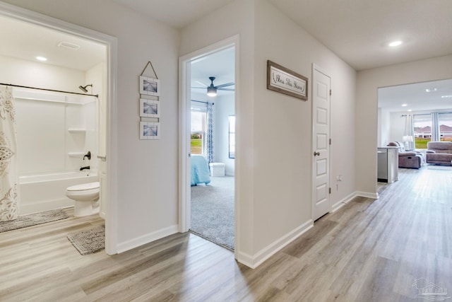 hall with light wood-style flooring, baseboards, and recessed lighting