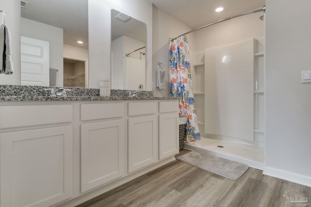 full bathroom featuring double vanity, recessed lighting, wood finished floors, and a shower stall