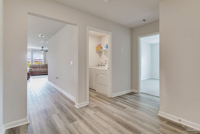 hallway with light wood-type flooring, baseboards, and washer and clothes dryer