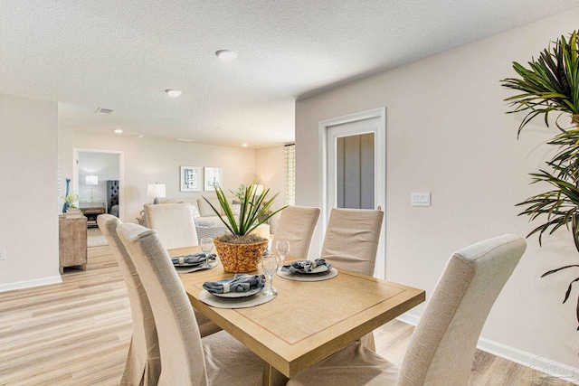 dining room with light hardwood / wood-style flooring and a textured ceiling