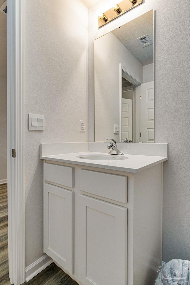 bathroom with vanity, wood-type flooring, and a textured ceiling