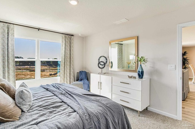 bedroom featuring light carpet and a textured ceiling