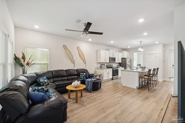 living room featuring sink, ceiling fan, and light hardwood / wood-style floors