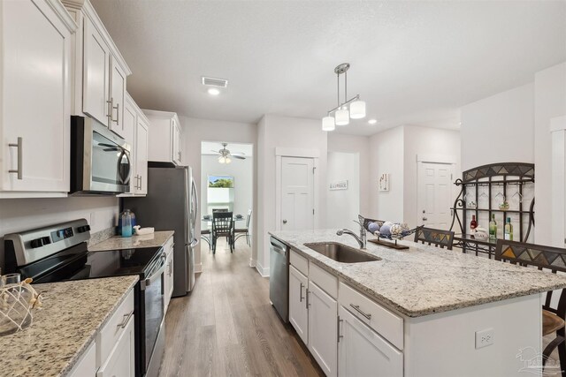 kitchen featuring appliances with stainless steel finishes, wood-type flooring, sink, and a kitchen island with sink