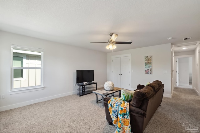 living room featuring light carpet, ceiling fan, and a textured ceiling