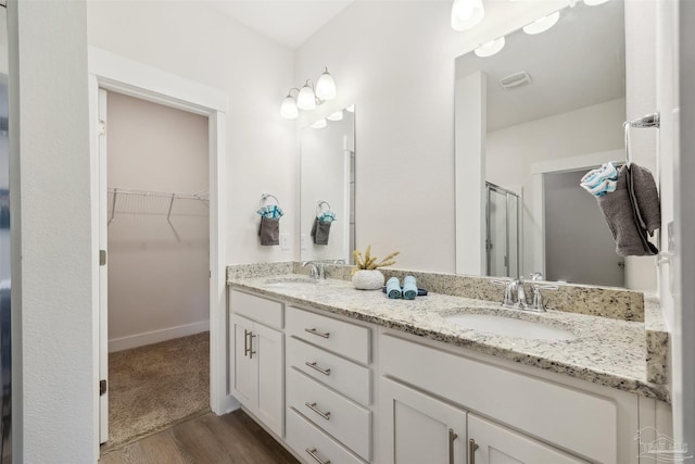 bathroom featuring wood-type flooring, double sink vanity, and a shower with door