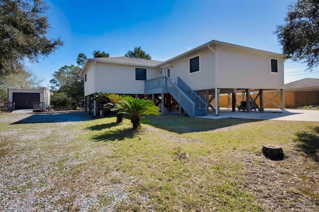 rear view of house featuring driveway, stairway, a carport, and a yard