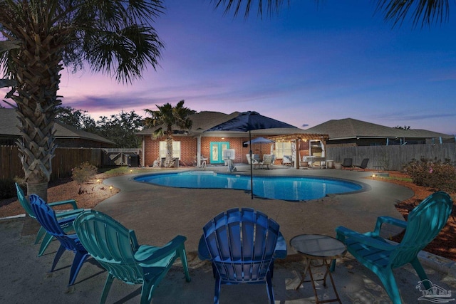 pool at dusk with a patio, an outdoor structure, a fenced backyard, and a fenced in pool