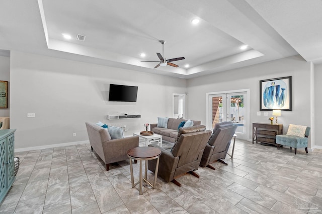 living room with a ceiling fan, visible vents, baseboards, french doors, and a tray ceiling