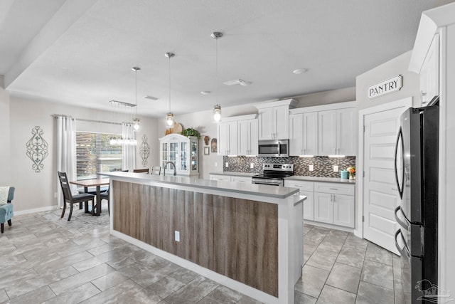 kitchen featuring a center island with sink, stainless steel appliances, light countertops, backsplash, and white cabinets