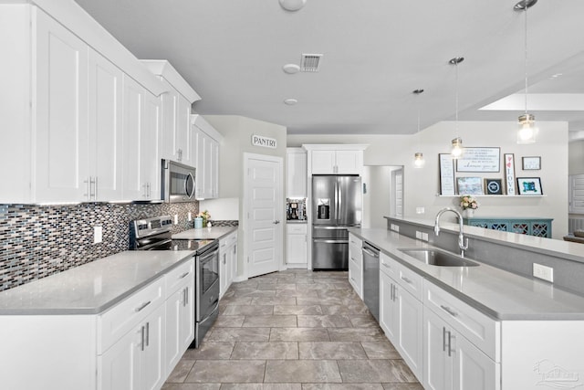 kitchen featuring stainless steel appliances, a spacious island, a sink, white cabinetry, and backsplash