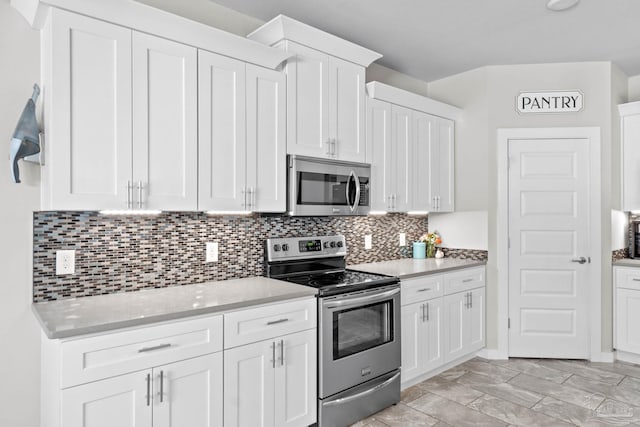 kitchen with appliances with stainless steel finishes, light countertops, and white cabinetry