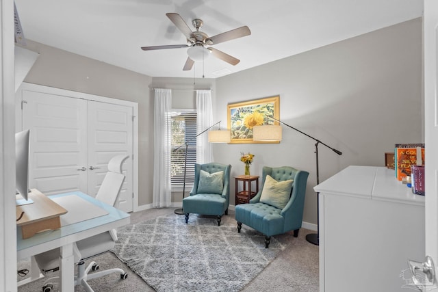 carpeted office space featuring ceiling fan and baseboards