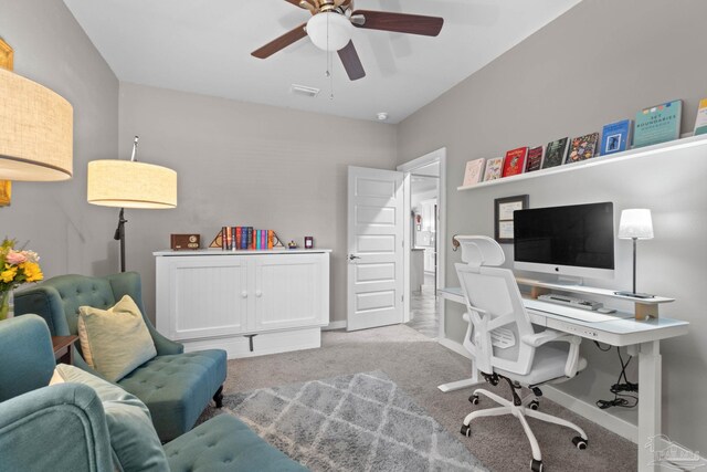 carpeted office space with baseboards, visible vents, and a ceiling fan