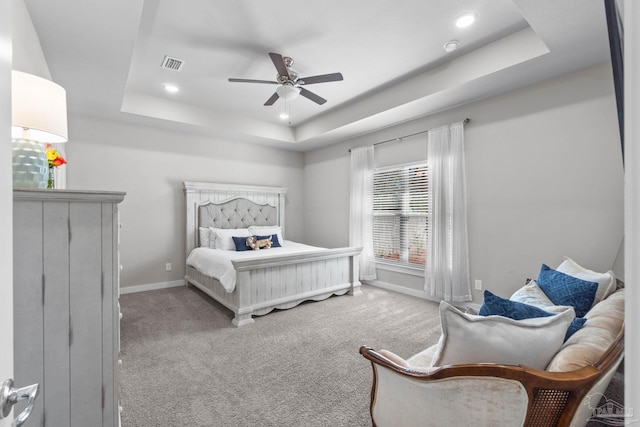 carpeted bedroom with a tray ceiling, visible vents, baseboards, and recessed lighting