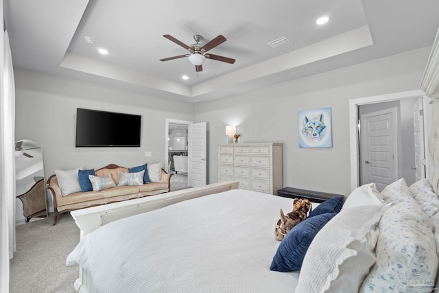 bedroom with light carpet, a tray ceiling, visible vents, and recessed lighting