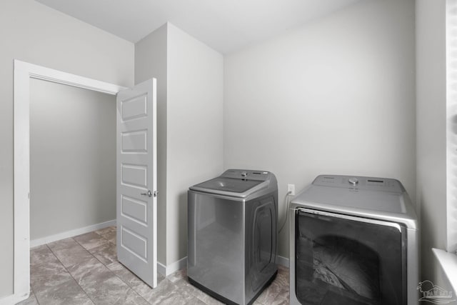 laundry area with laundry area, baseboards, and washer and clothes dryer