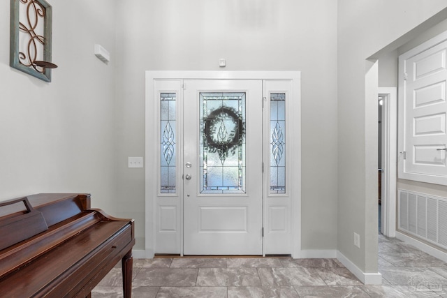 foyer entrance with visible vents and baseboards