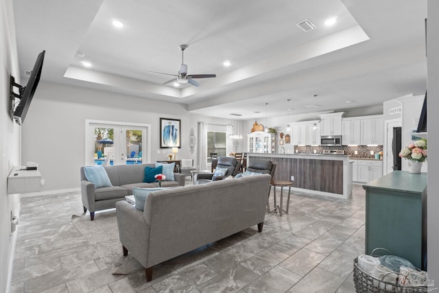 living room featuring french doors, a raised ceiling, visible vents, and baseboards