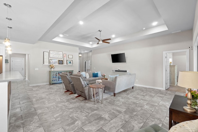 living room featuring a ceiling fan, a tray ceiling, baseboards, and recessed lighting