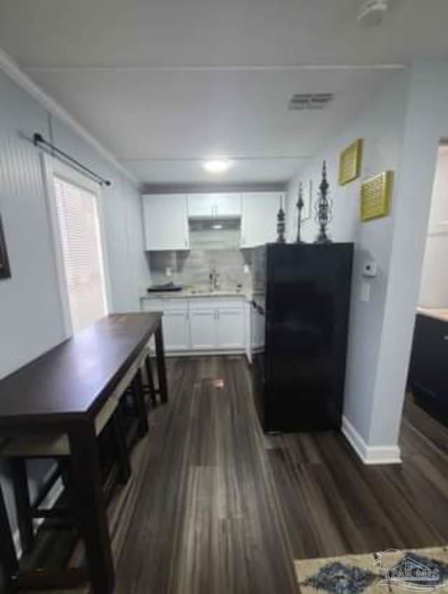 3111 Zepp Ln, Pace, FL 32571 - kitchen with freestanding refrigerator, dark wood-type flooring, white cabinets, light countertops, and tasteful backsplash