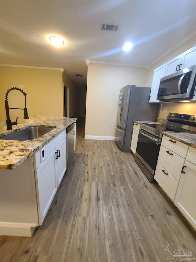 3111 Zepp Ln, Pace, FL 32571 - kitchen with stainless steel appliances, light wood-style floors, white cabinets, light stone countertops, and crown molding