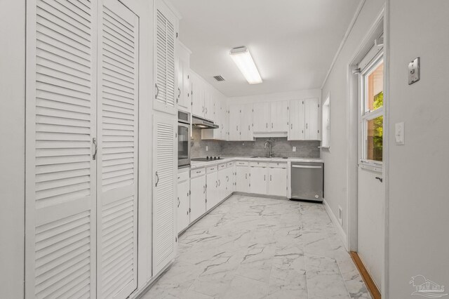 kitchen featuring tasteful backsplash, light countertops, appliances with stainless steel finishes, under cabinet range hood, and marble finish floor