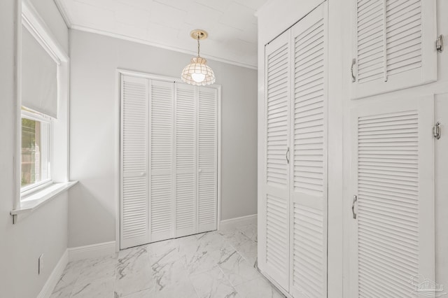 interior space featuring crown molding, baseboards, marble finish floor, and two closets