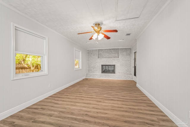 unfurnished living room with a ceiling fan, wood finished floors, ornamental molding, and visible vents