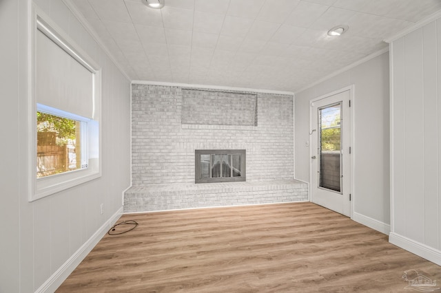 unfurnished living room with brick wall, crown molding, and wood finished floors