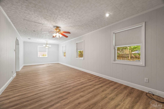 unfurnished room featuring baseboards, ornamental molding, ceiling fan with notable chandelier, and wood finished floors