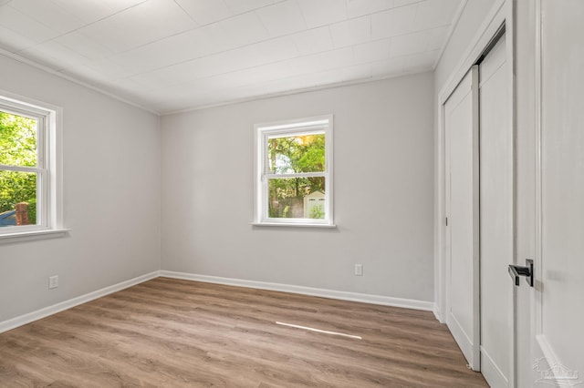unfurnished bedroom with wood finished floors, baseboards, and a closet