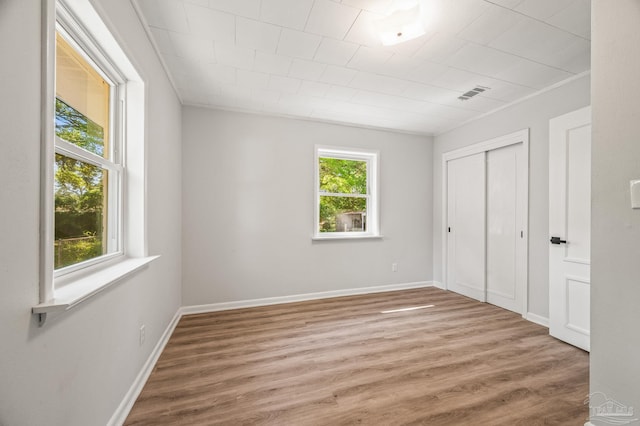 unfurnished bedroom with visible vents, a closet, baseboards, and wood finished floors