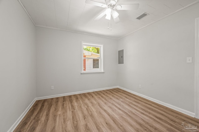 unfurnished room with visible vents, baseboards, electric panel, light wood-type flooring, and crown molding