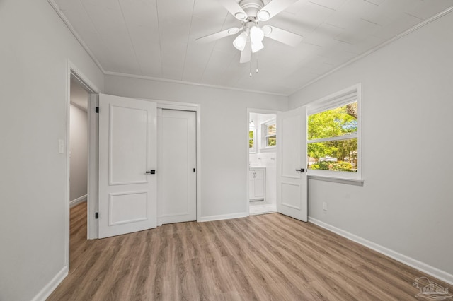 unfurnished bedroom with baseboards, light wood-type flooring, a closet, crown molding, and connected bathroom