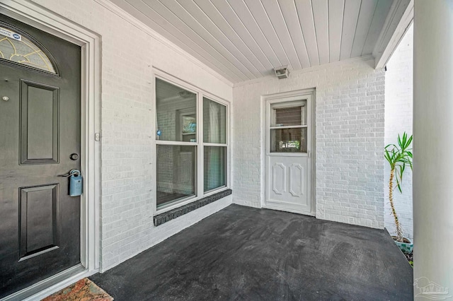 entrance to property featuring brick siding and a porch