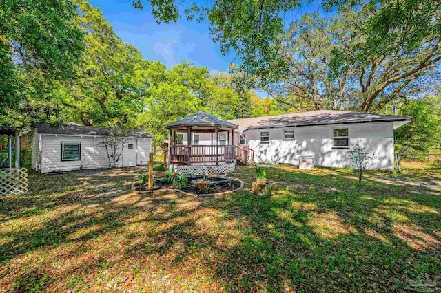 back of property with an outbuilding, a gazebo, a deck, fence, and a lawn