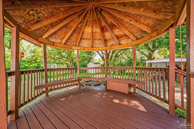 wooden terrace featuring an outbuilding, a storage unit, and a gazebo