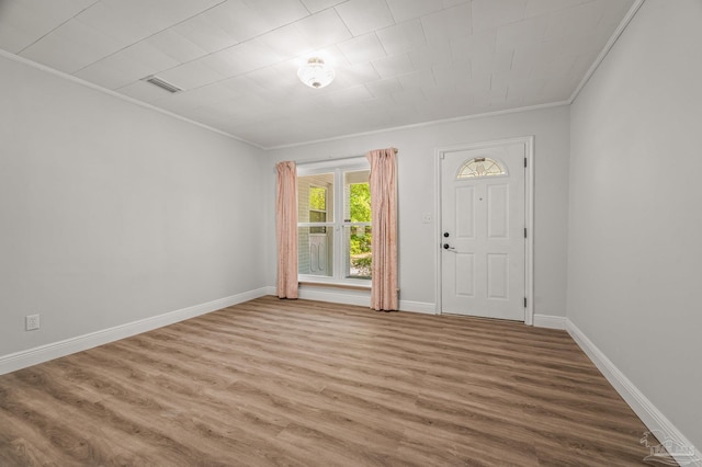 foyer featuring wood finished floors, baseboards, ornamental molding, and visible vents