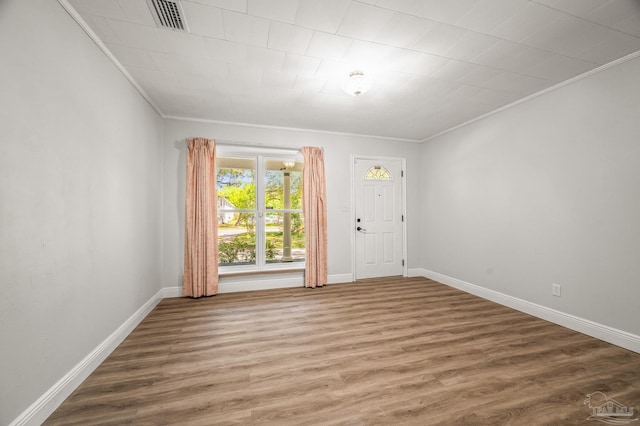 unfurnished room featuring ornamental molding, visible vents, baseboards, and wood finished floors