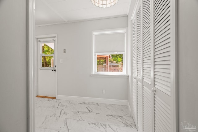 hall featuring crown molding, baseboards, and marble finish floor
