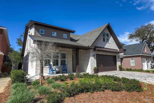 view of front of property featuring decorative driveway, brick siding, and covered porch