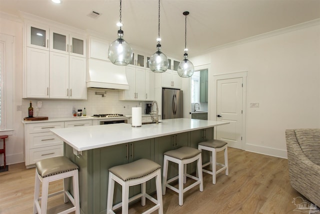 kitchen featuring visible vents, custom exhaust hood, stainless steel appliances, light wood-style floors, and tasteful backsplash