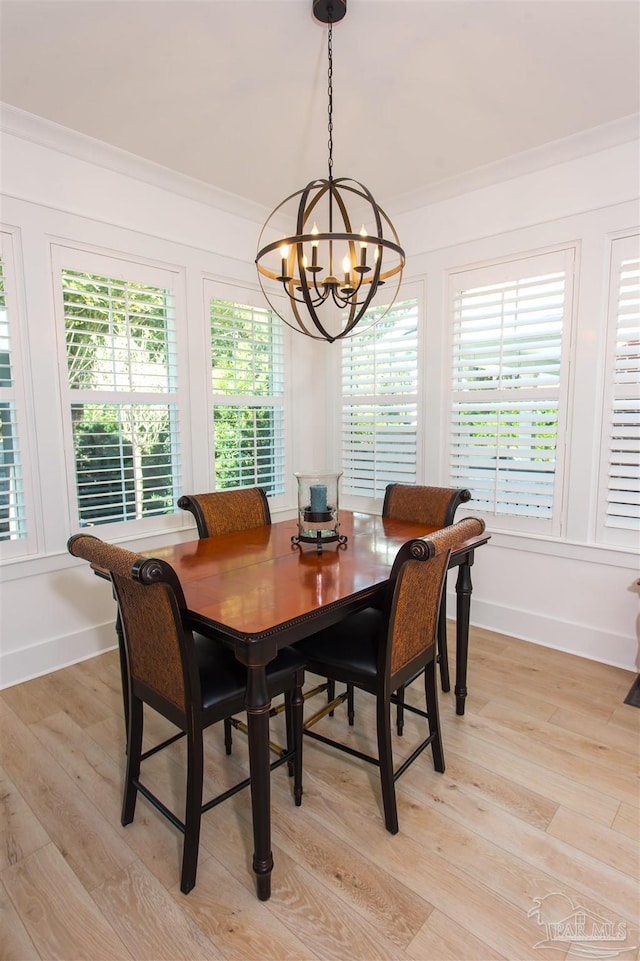 dining room with a chandelier, light wood-type flooring, baseboards, and ornamental molding