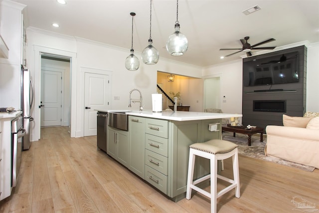 kitchen with a ceiling fan, stainless steel appliances, a sink, light countertops, and crown molding