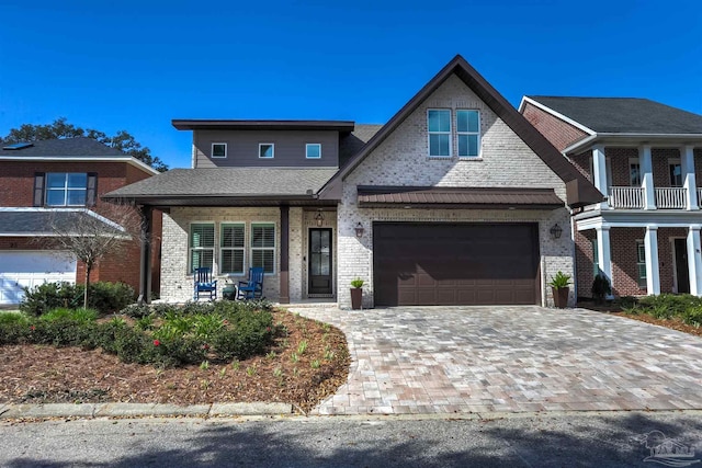 view of front of property featuring decorative driveway, brick siding, covered porch, and an attached garage