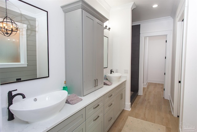 bathroom with a sink, an inviting chandelier, wood finished floors, and double vanity