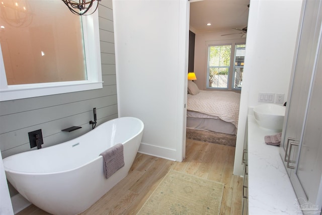 ensuite bathroom with connected bathroom, baseboards, ceiling fan, wood finished floors, and a freestanding tub