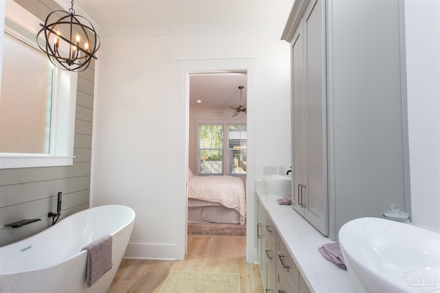 bathroom featuring wood finished floors, a freestanding tub, ornamental molding, ceiling fan with notable chandelier, and connected bathroom