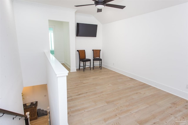 interior space with wood finished floors, baseboards, ceiling fan, vaulted ceiling, and crown molding